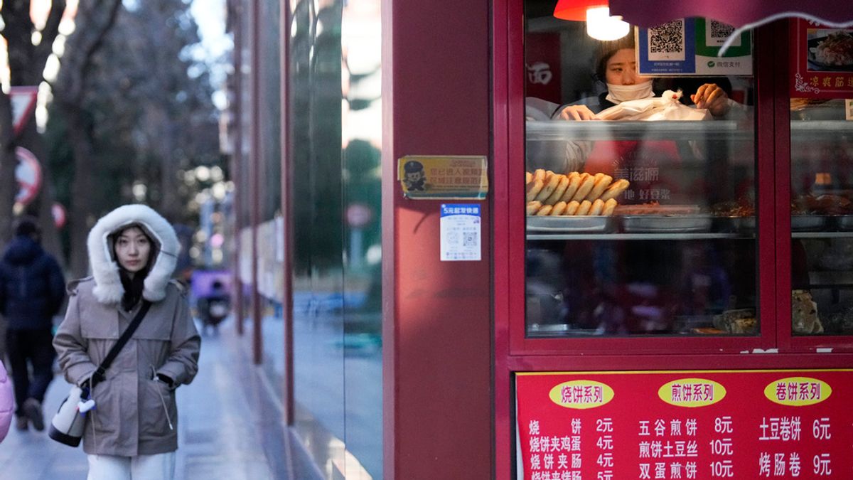 2025年1月8日。中國北京,一個寒冷的早晨,一名員工在餐廳裡擺設食物,而另一名婦女正在散步。 (AP)中國經濟 2025年1月8日。中國北京,一個寒冷的早晨,一名員工在餐廳裡擺設食物,而另一名婦女正在散步。 (AP)中國經濟