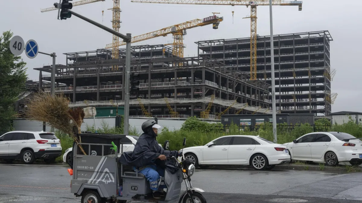 2024年7月25日。清道夫騎車經過北京的一處工地。(AP)