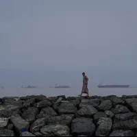On March 11, 2026, a man walks along the coast of the Strait of Hormuz in Khor Fakkan, UAE, with oil tankers and cargo ships visible in the distance. (AP) On March 11, 2026, a man walks along the coast of the Strait of Hormuz in Khor Fakkan, UAE, with oil tankers and cargo ships visible in the distance. (AP)
