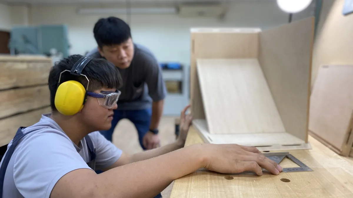 參加「第53屆全國技能競賽」家具木工職類的董志宣,在訓練師指導下進行家具箱體試裝,並確認水平直角面及整體總尺寸。(圖/勞動力發展署北分署提供)