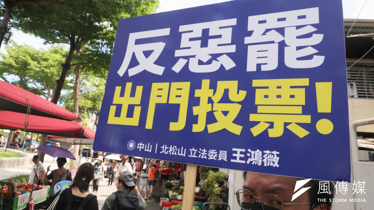 圖為國民黨立委王鴻薇工作人員舉牌宣傳出門投票反罷免。(柯承惠攝)