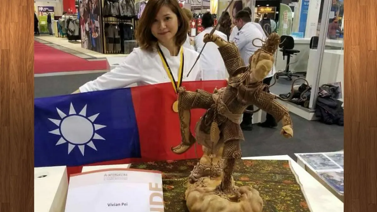裴志偉的藝術麵包「銳變」獲得「國際餐飲展覽暨烹飪比賽」金牌後,在會場展示她隨身帶著的中華民國國旗。(作者提供)