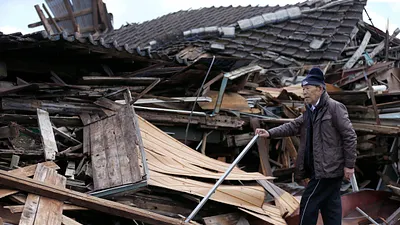 日本一名長者經過倒塌房舍前。(美聯社)