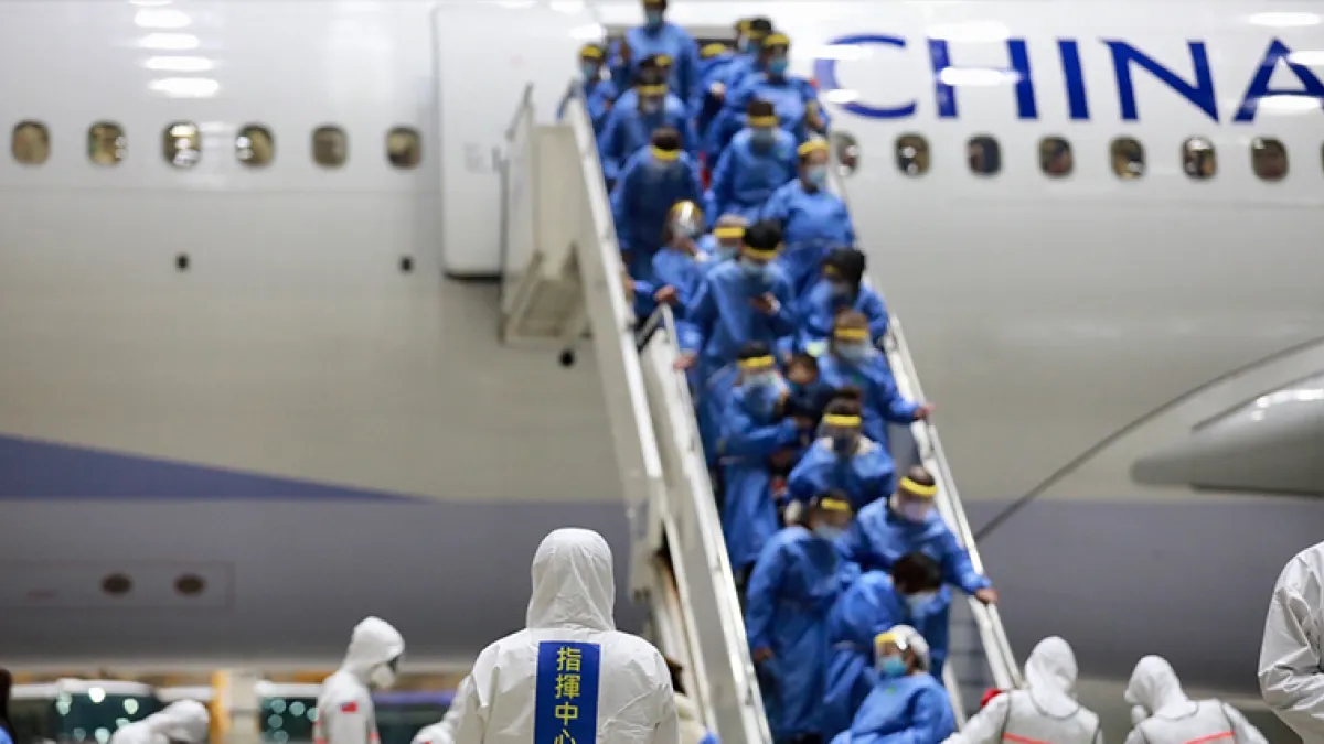 穿著防護衣、配戴口罩的返台國人陸續下機,配合相關檢疫措施。(圖/中央流行疫情指揮中心提供)