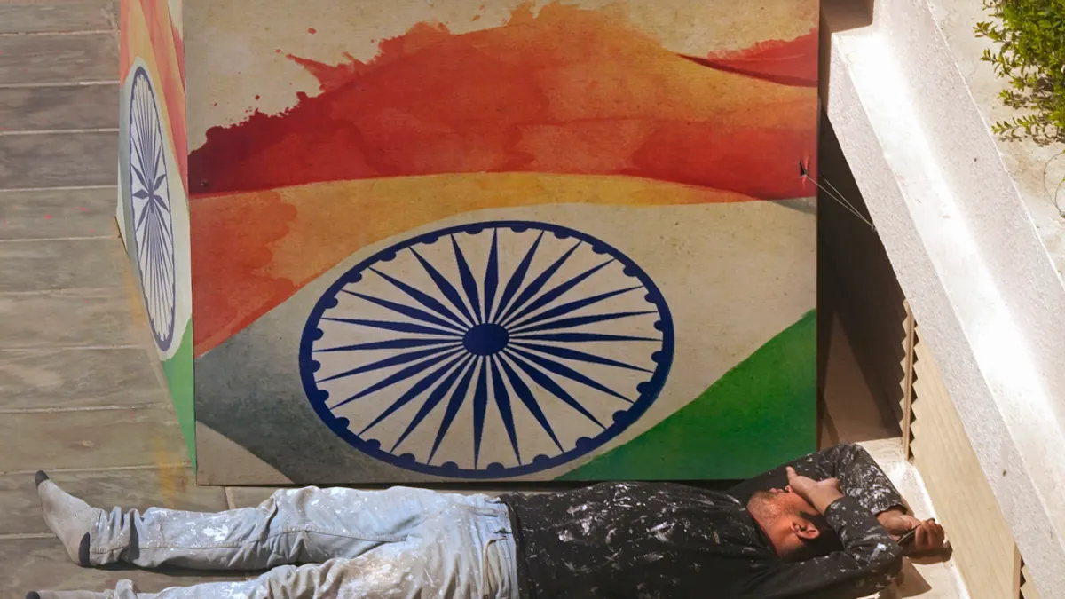 2024年3月20日。印度新德里,一名工人在畫有印度國旗的剪紙旁小憩。(美聯社) 2024年3月20日。印度新德里,一名工人在畫有印度國旗的剪紙旁小憩。(美聯社)