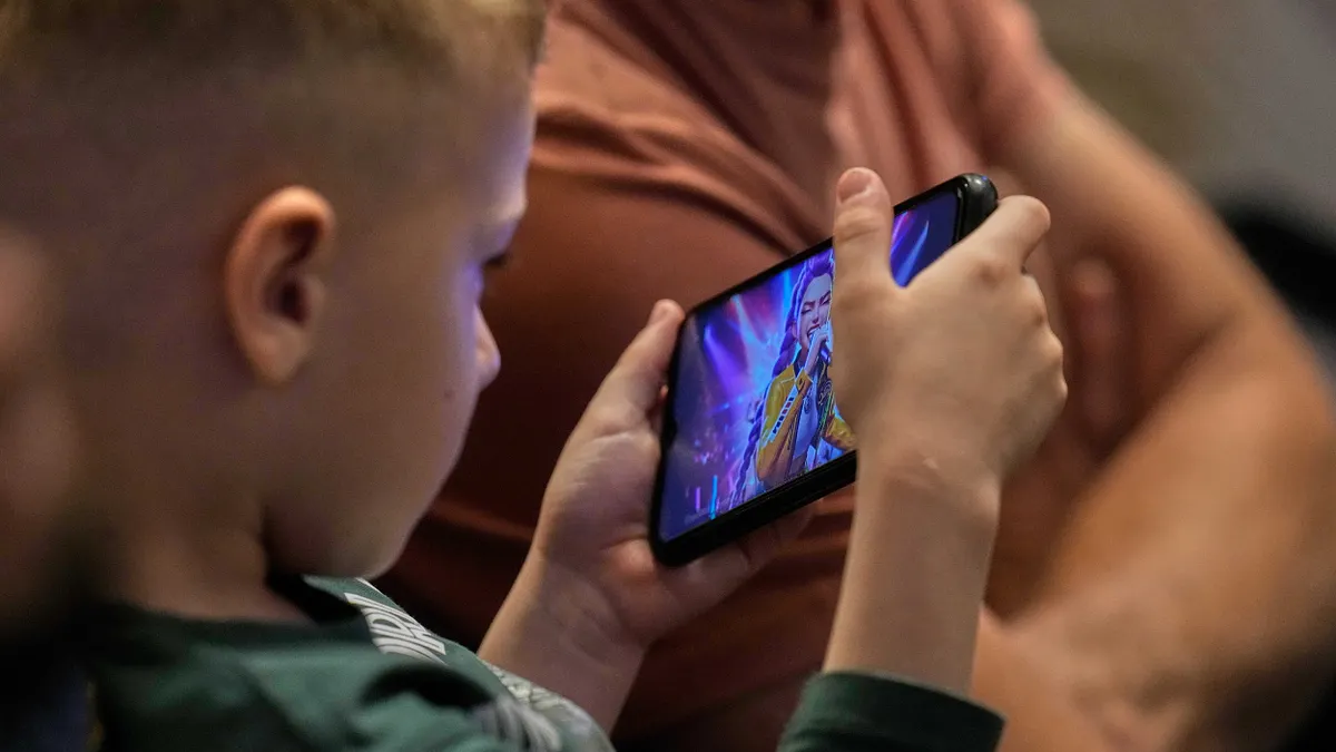 2026年4月11日,教宗良十四世在梵蒂岡聖彼得大教堂主持和平守夜活動,一個小朋友正在用手機觀看《獵魔女團》。(美聯社)