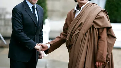 法國前總統薩科齊疑似收受前利比亞獨裁者格達費的政治獻金,20日遭檢調約談。圖為2007年12月10日,薩科齊(左)與格達費(右)在法國握手。(AP)