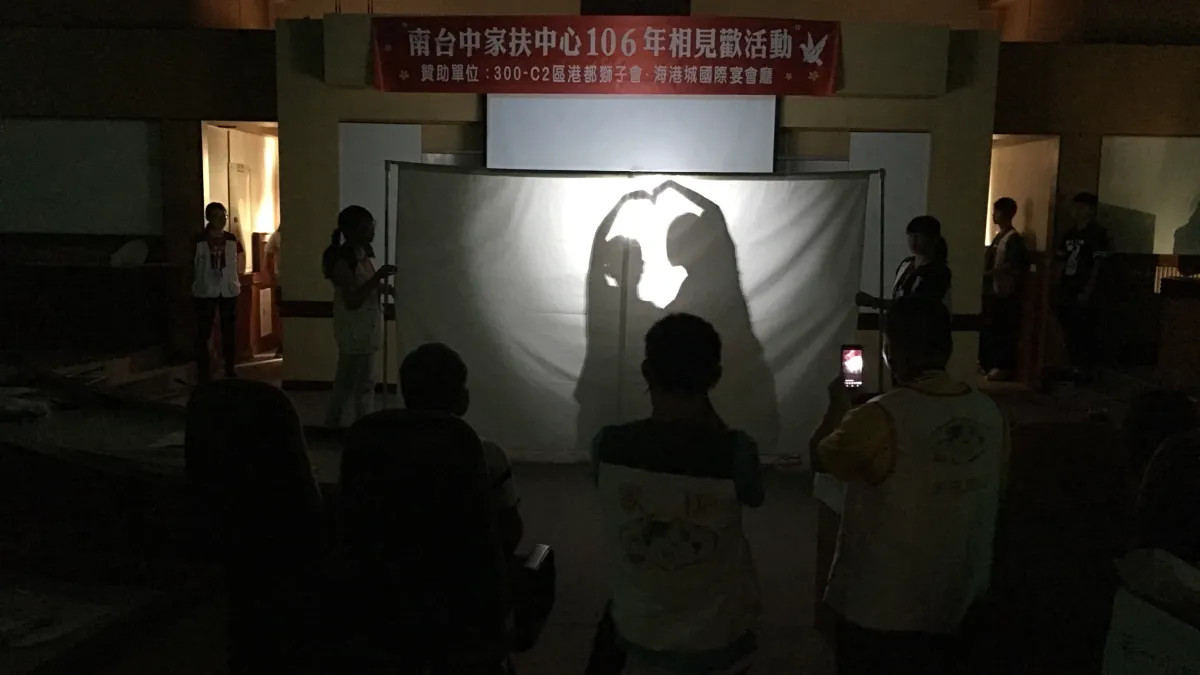 活動透過光影的投射,映照出認養人與認養兒童一起比出的愛心剪影,象徵「愛,如影隨形」。(圖/南台中家扶提供)