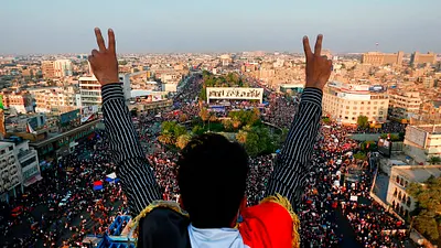 一名伊拉克示威者對著巴格達解放廣場的人群比出勝利手勢。(美聯社)