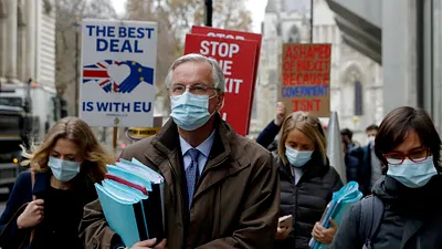 脫歐談判代表巴尼耶(Michel Barnier),他身後的倫敦民眾正高舉「反對無協議脫歐」的標語。(美聯社)