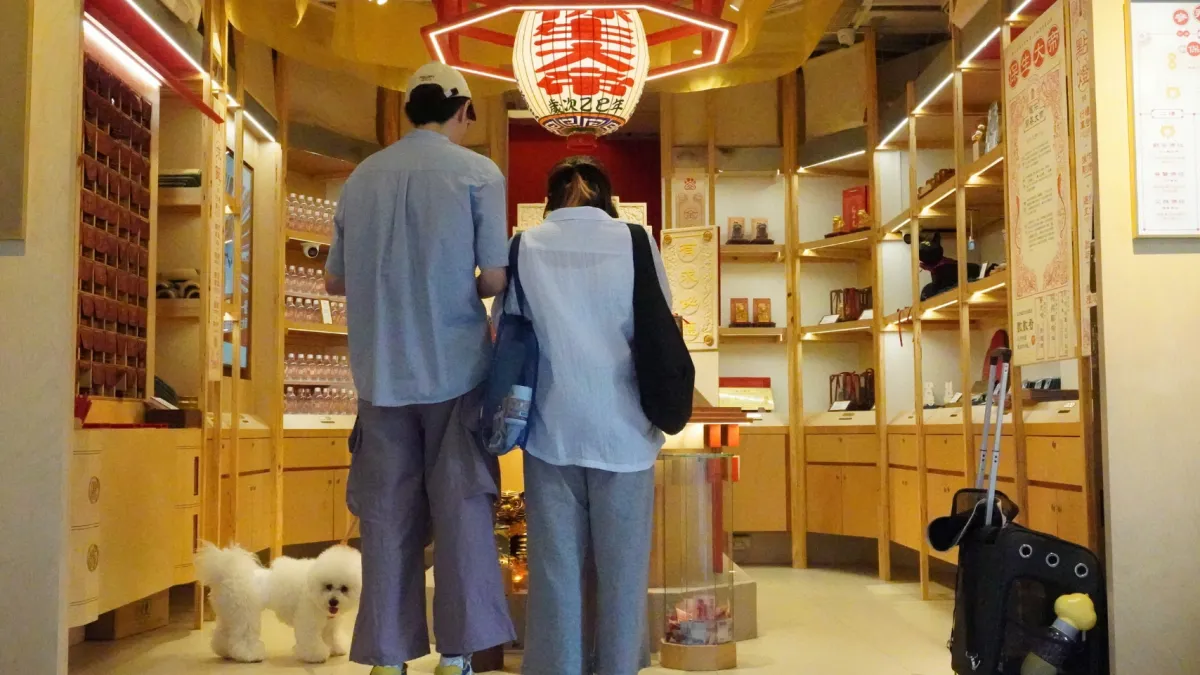 A couple and their bichon frise at Cho Yuu Temple, which is unstaffed on most days. The wall of small drawers at left holds the temple's oracle plaques. (Photo by Chang Yu-ping)