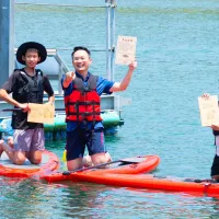 桃園市副市長蘇俊賓出席百吉國小「水上畢業典禮」,陪同畢業生划著 SUP 立板,尋找畢業證書。(圖/桃園市政府提供) 桃園市副市長蘇俊賓出席百吉國小「水上畢業典禮」,陪同畢業生划著 SUP 立板,尋找畢業證書。(圖/桃園市政府提供)