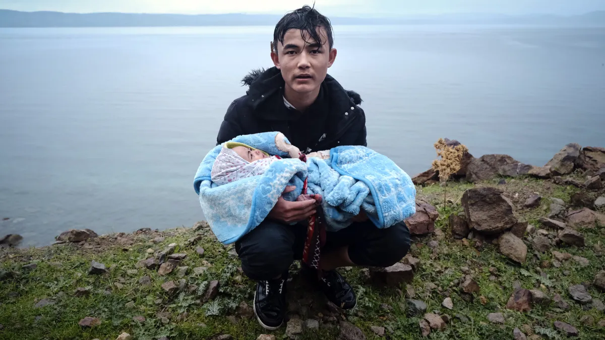 2020年3月,抵達希臘萊斯沃斯島(Lesbos)的敘利亞難民,一名男子抱著嬰兒登陸(AP)