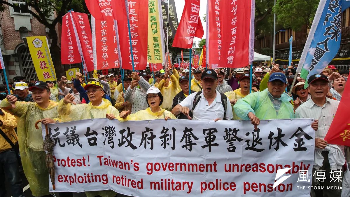 退休警消人員4月24日舉行警消不服從遊行,手持「抗議台灣政府剝奪軍警退休金」布條。(資料照,顏麟宇攝)