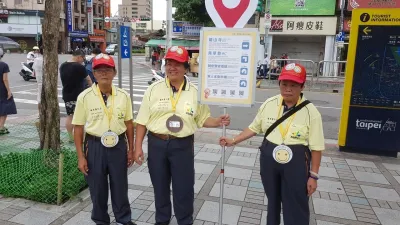 臺北市的「城市導引員」計畫每日讓 6 名街友在龍山寺捷運站出口以手舉牌方式,提供旅客附近的旅遊景點指引。週一至週五,每人每日工作時數為 4 小時,工作 50 分鐘可以休息 10 分鐘。(圖/臺北市政府就業服務處提供)