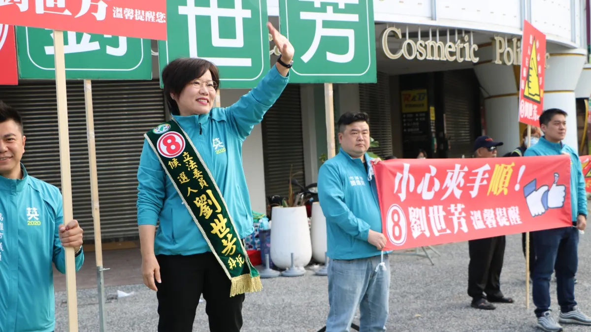 民進黨立委劉世芳(左)7日進行路口拜票時,特別準備道具,諷刺對手黃昭順「夾手他人」一事。(劉世芳競辦提供)
