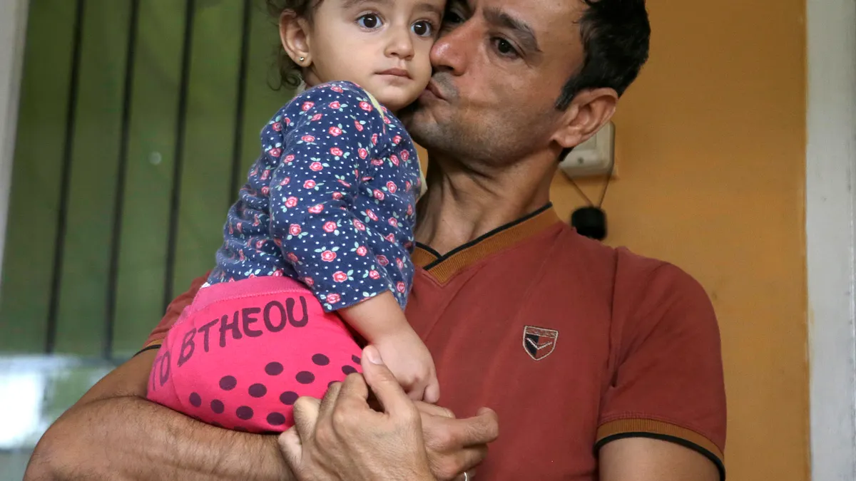 懷抱一絲希望、等待入境美國的伊拉克難民父女(AP)