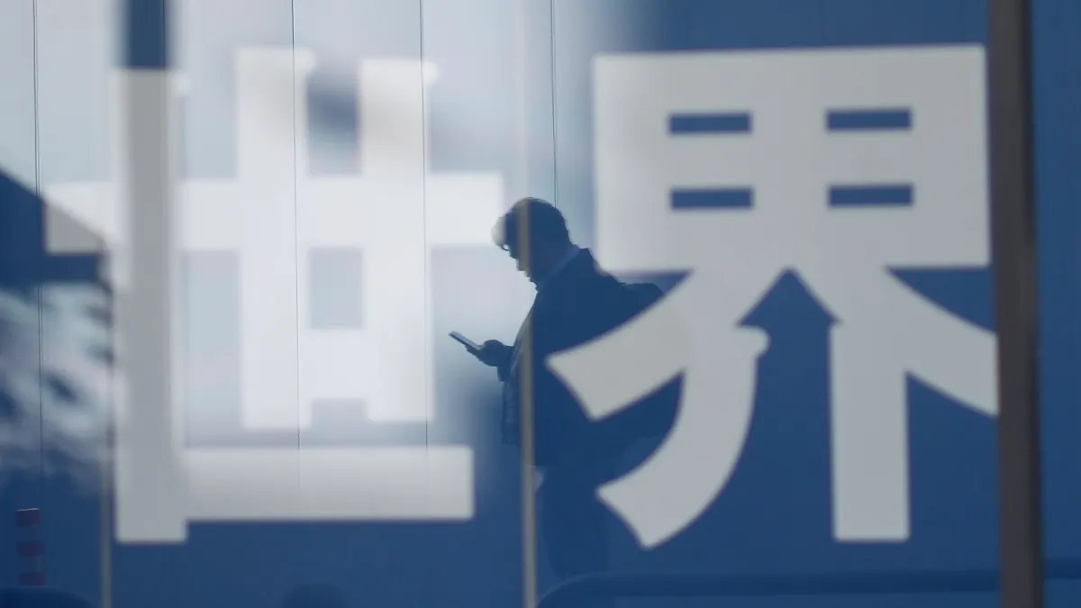 2025年12月15日,日本東京一名路人的剪影倒映在商店櫥窗上,旁邊寫著日文漢字「世界」。(美聯社)
