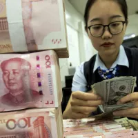 中国銀行の行員が人民元と米ドルの紙幣を数える。(写真/AP通信) 中国銀行の行員が人民元と米ドルの紙幣を数える。(写真/AP通信)
