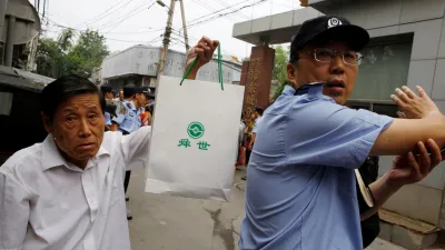 2018年8月27日,P2P投資計劃的受害人在北京東城區公安分局前面請願,一名男子拿著帶有P2P貸方徽標的袋子。(美國之音)