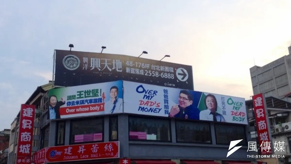 連的前特助、國民黨台北市議員參選人徐弘庭在這幅諷連看版旁邊,掛上「Over Whose Body?」的廣告看版,重提王世堅帶女助理上汽車旅館的往事。(羅暐智攝)