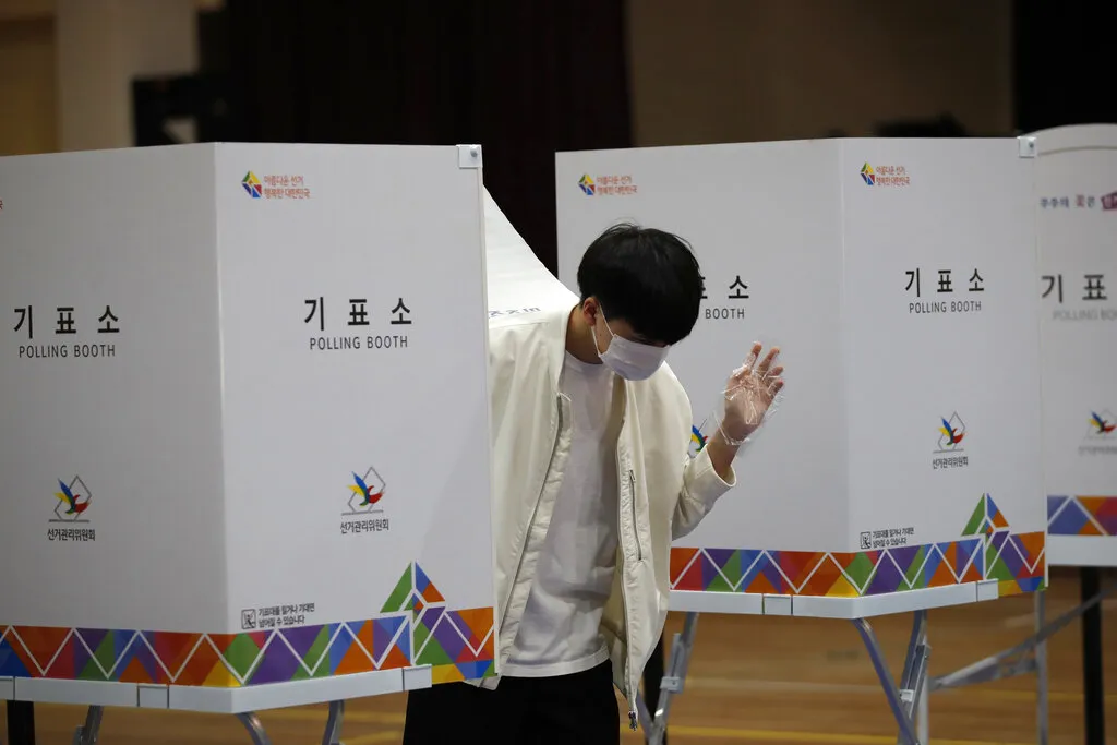 南韓4月15日舉行國會大選，由於新冠肺炎疫情仍未解除，民眾與投票所人員都嚴陣以待、手套口罩戴好戴滿。（美聯社）