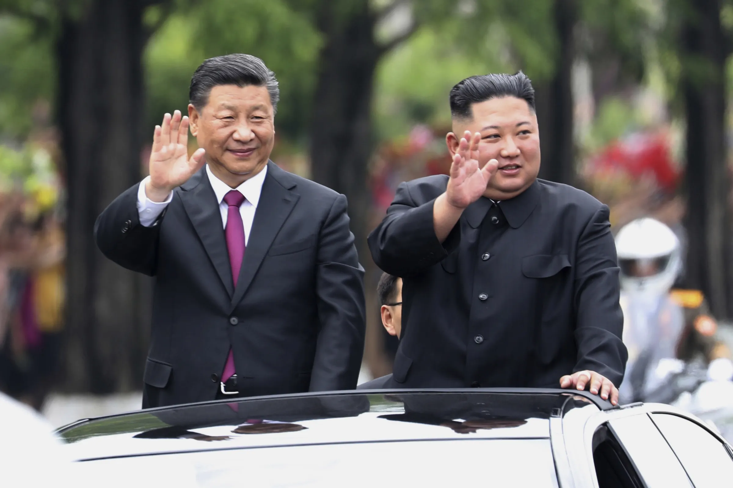 2019年6月20日，中國國家主席習近平（左）和北韓領導人金正恩在平壤街頭對民眾揮手示意。（美聯社）