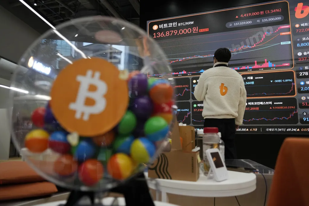2024年11月21日。在韓國首爾的Bithumb加密貨幣交易所休息室，一名員工在看顯示比特幣和其他加密貨幣價格的電子看板。（AP）