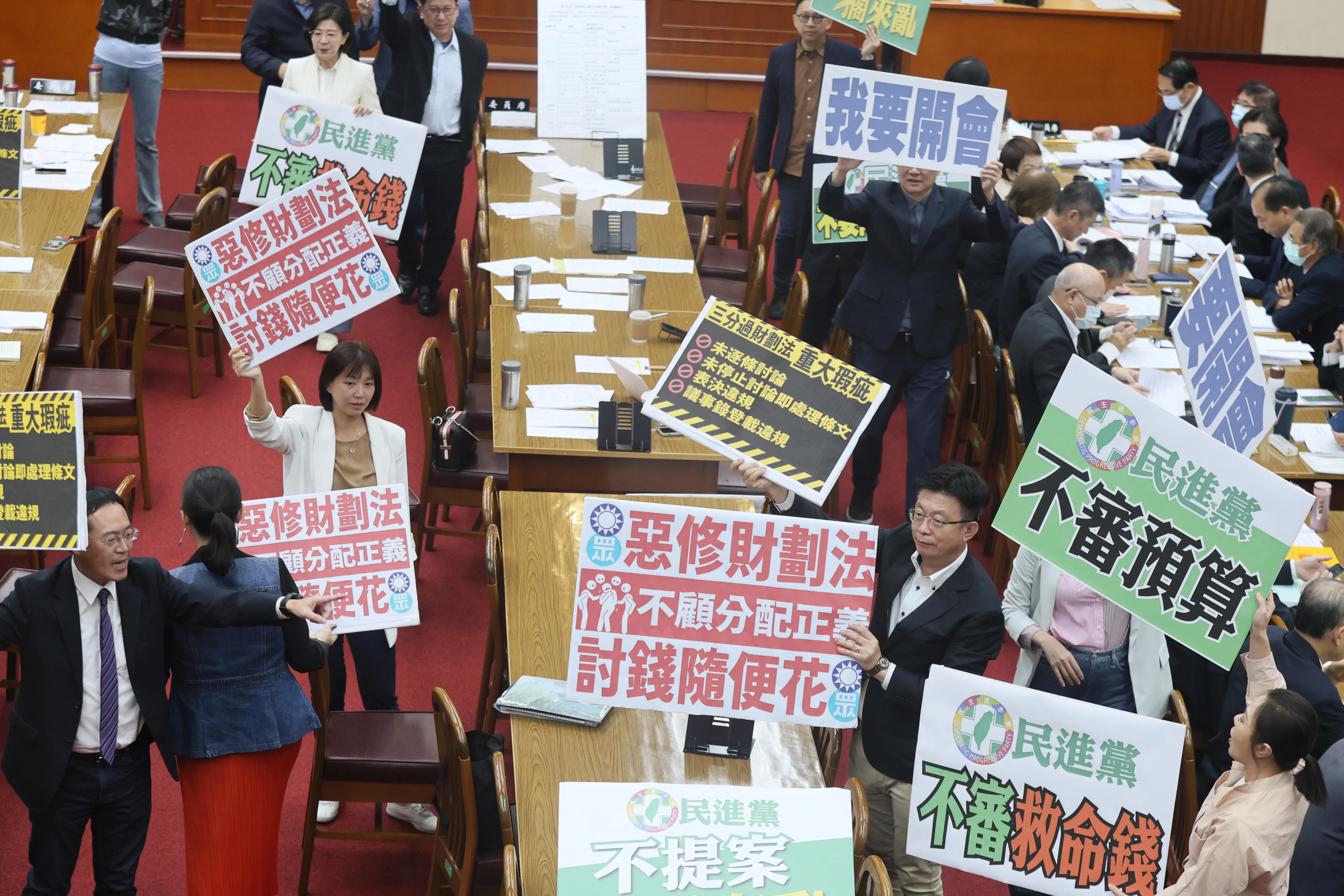 20241111-立法院財委会与野党の委員11日配分法修法会議で互いに論争、両者はそれぞれの立場を表すプラカードを掲げた。（柯承惠撮）