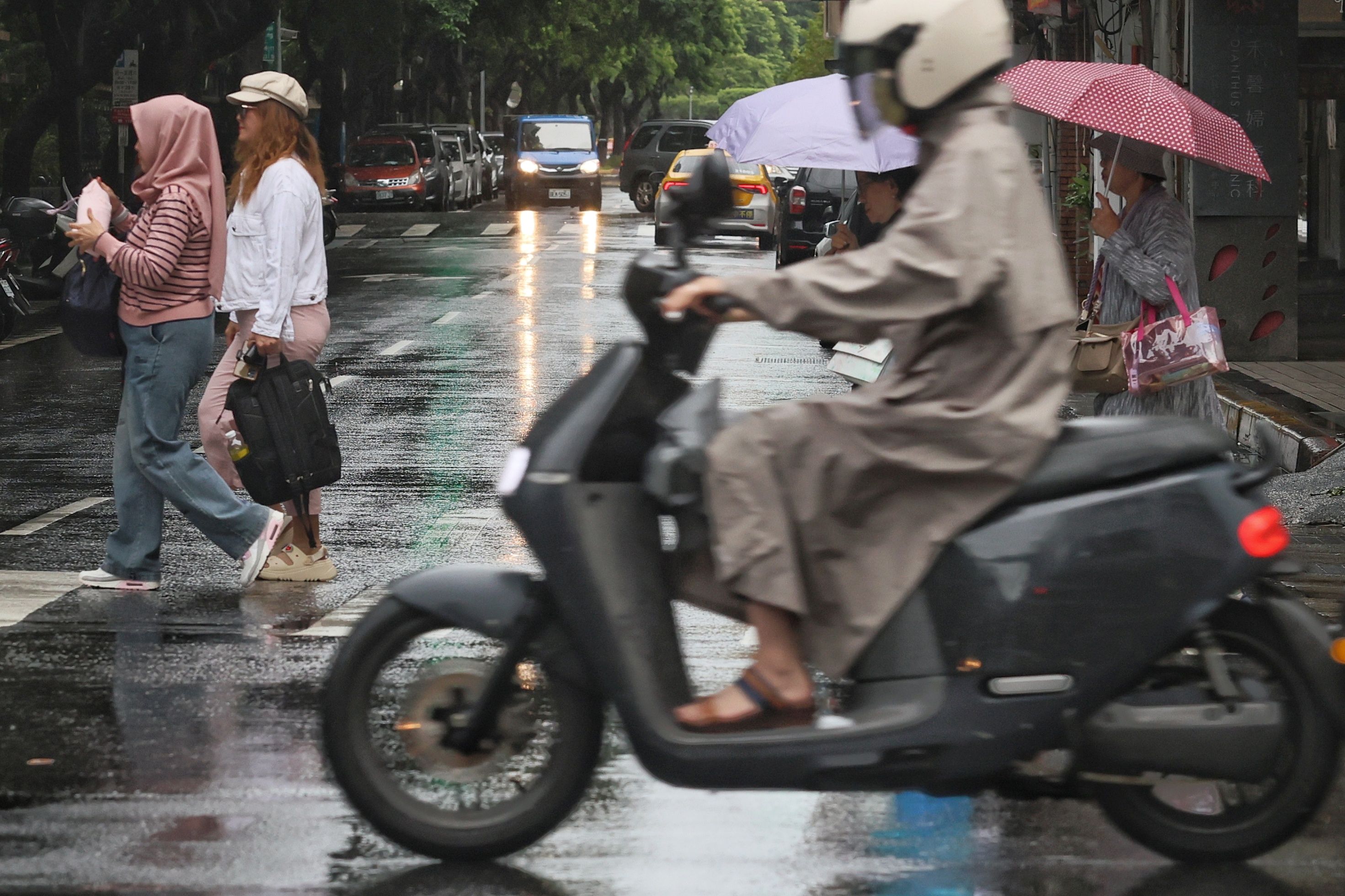 間歇雨勢、 街頭行人、 機車騎士、 斑馬線、 穿越馬路。（柯承惠攝）