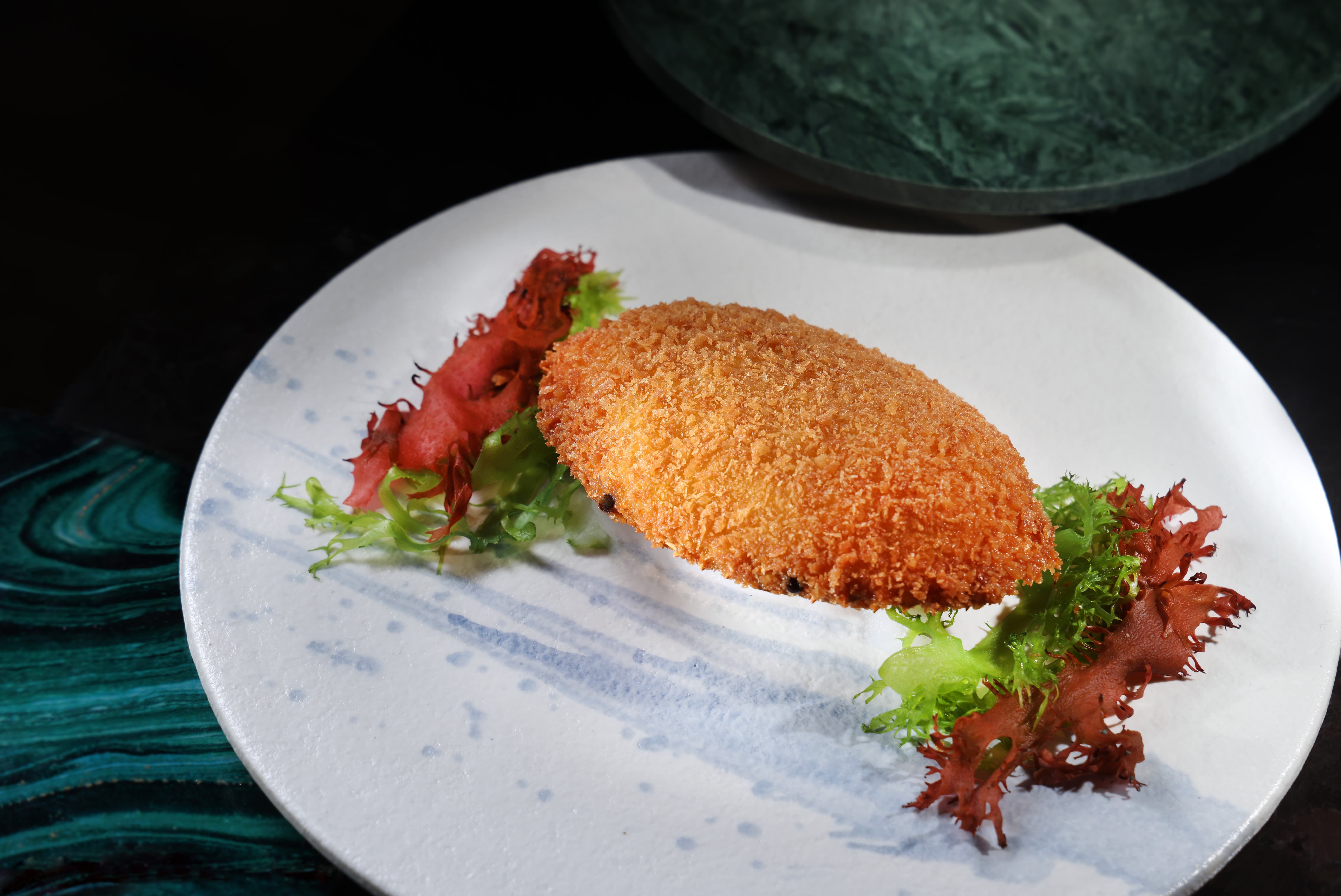 「麗晶軒」的招牌料理「脆釀鮮蟹蓋」凝聚粵菜精髓，將手工拆取的細緻鮮蟹肉填入蟹蓋中油炸至香脆金黃，展現香酥與嫩滑的雙重口感。