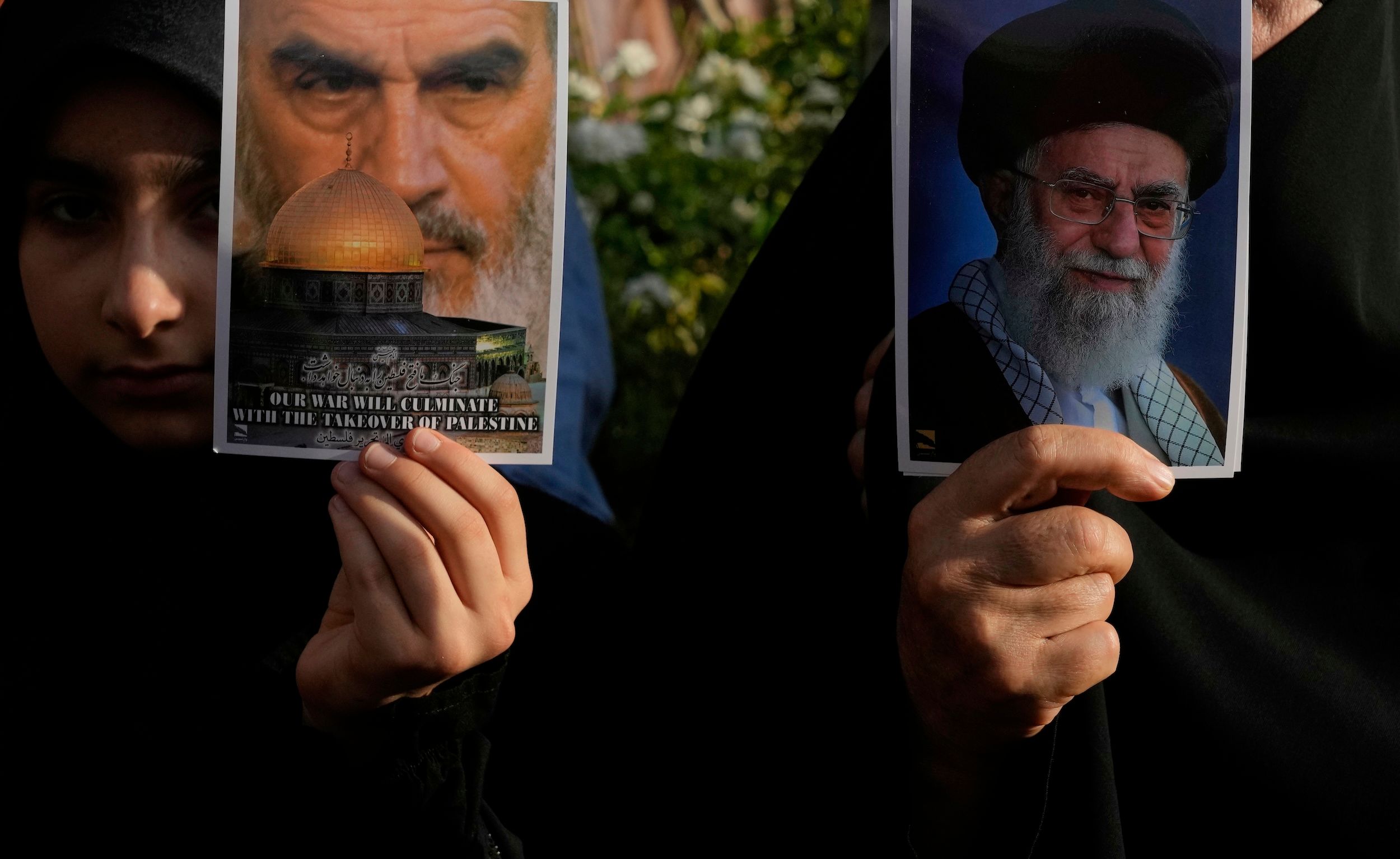  2025年6月22日，伊朗民眾在德黑蘭手持最高領袖哈米尼（右）及已故領袖何梅尼（左）的肖像上街抗議，譴責美國對伊朗多座城市的空襲。（美聯社）