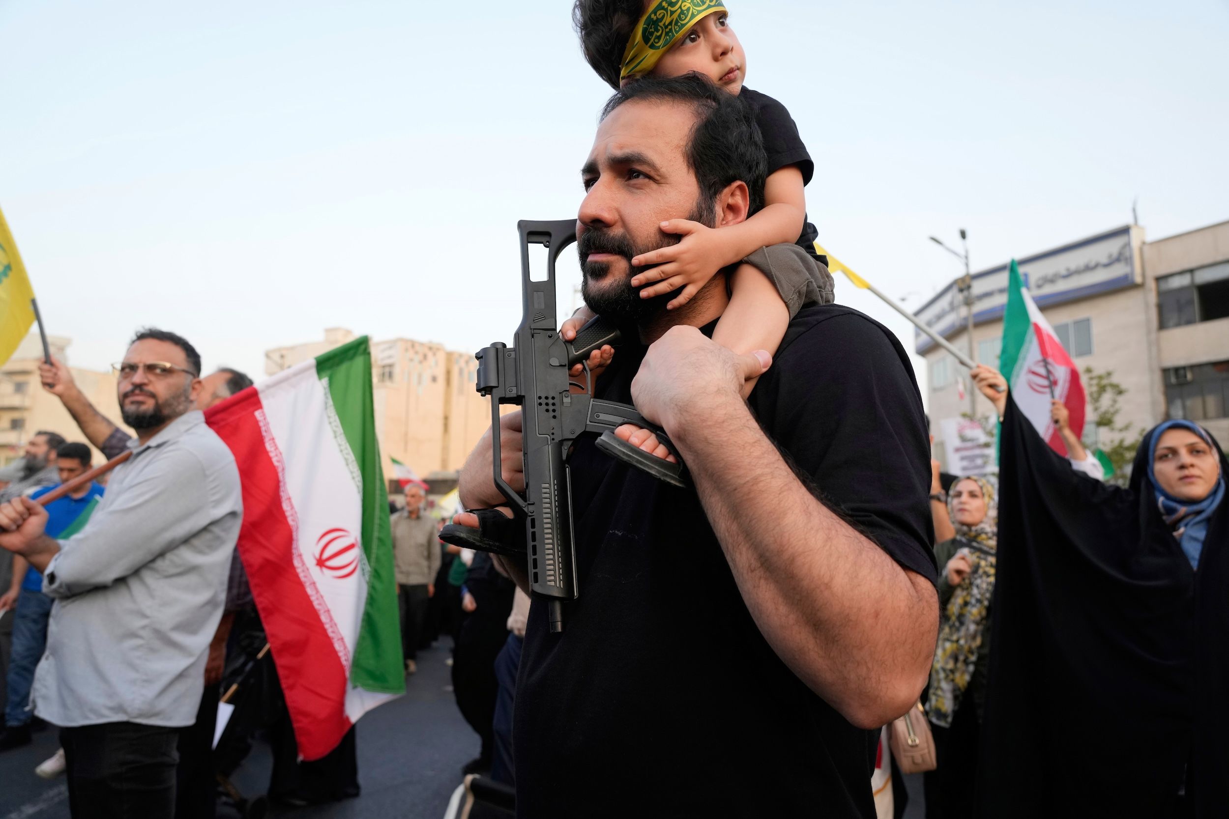 2025年6月24日、イラン・テヘラン市中心部のイスラム革命広場で行われた反米反イスラエル集会で、イラン人抗議者が息子を肩に担ぎ、手におもちゃの銃を持っている。（AP通信）