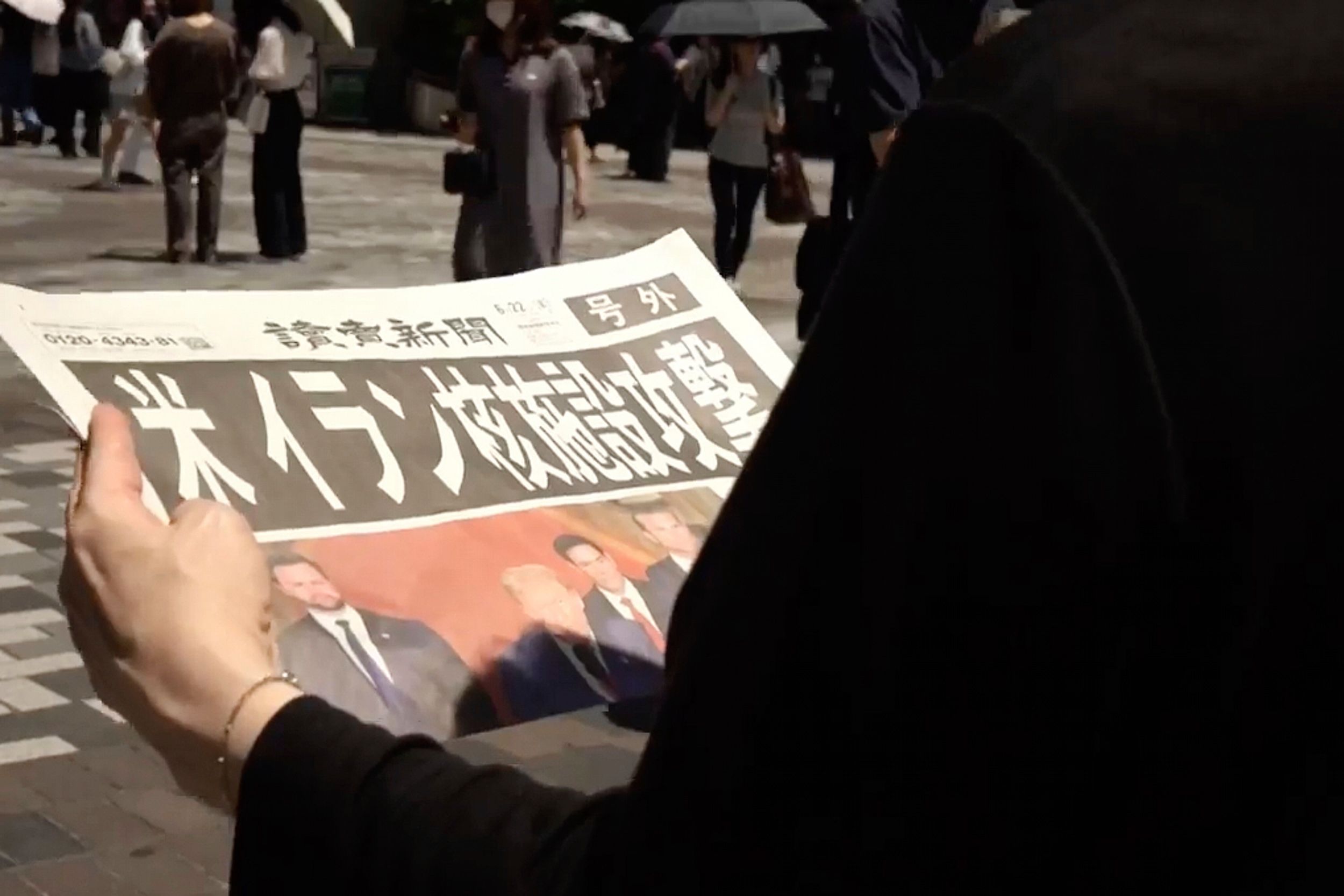 2025年6月22日，日本東京一位民眾在看報紙，頭條寫著「美國攻擊伊朗核設施」。（美聯社）