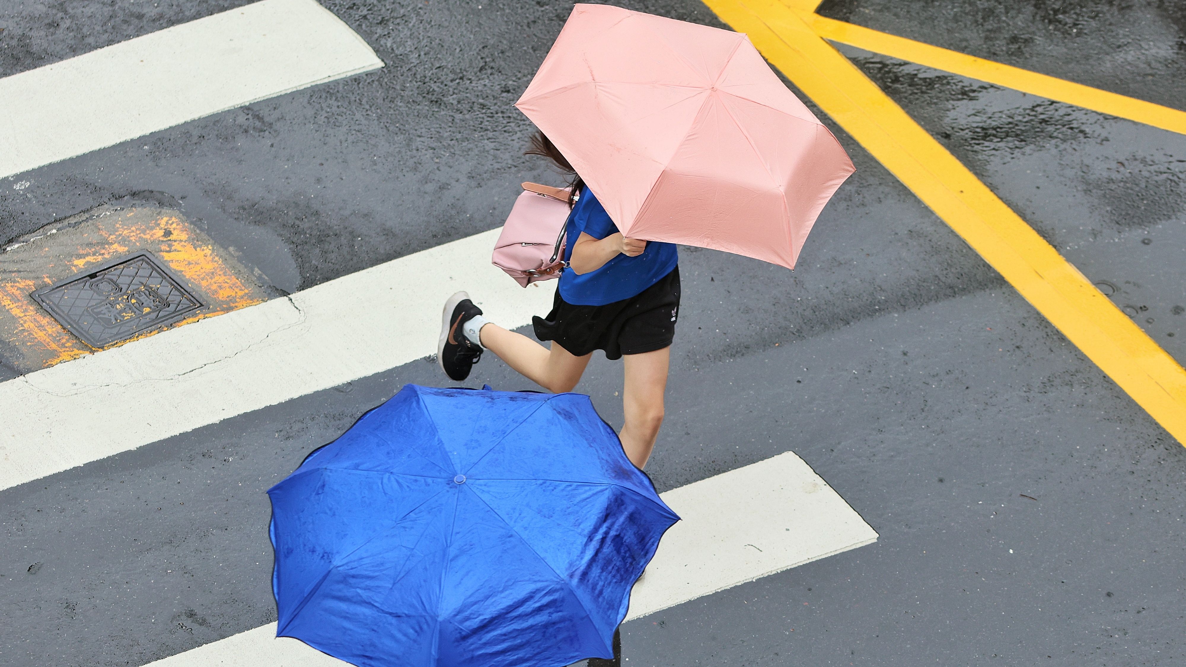 20250707-受颱風デービス的循環影響，台北市出現間歇雨勢，路上民眾遮雨。（柯承惠攝）