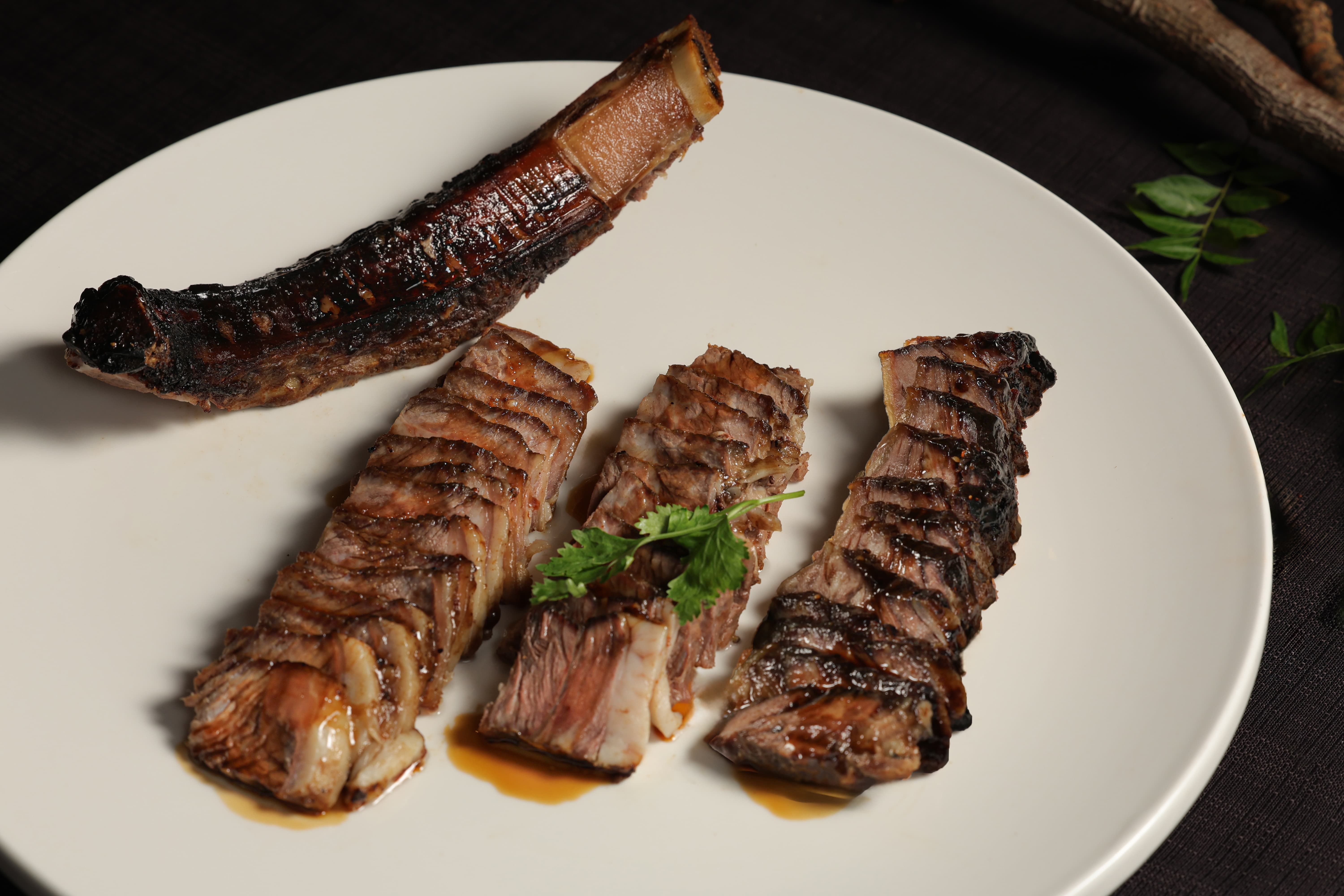 圖說：晶華軒主廚鄔海明在晶華軒推出以經典粵式燒臘技法打造的「蜜汁戰斧牛」，展現傳統烹藝與創意的結合。（圖/台北晶華提供）