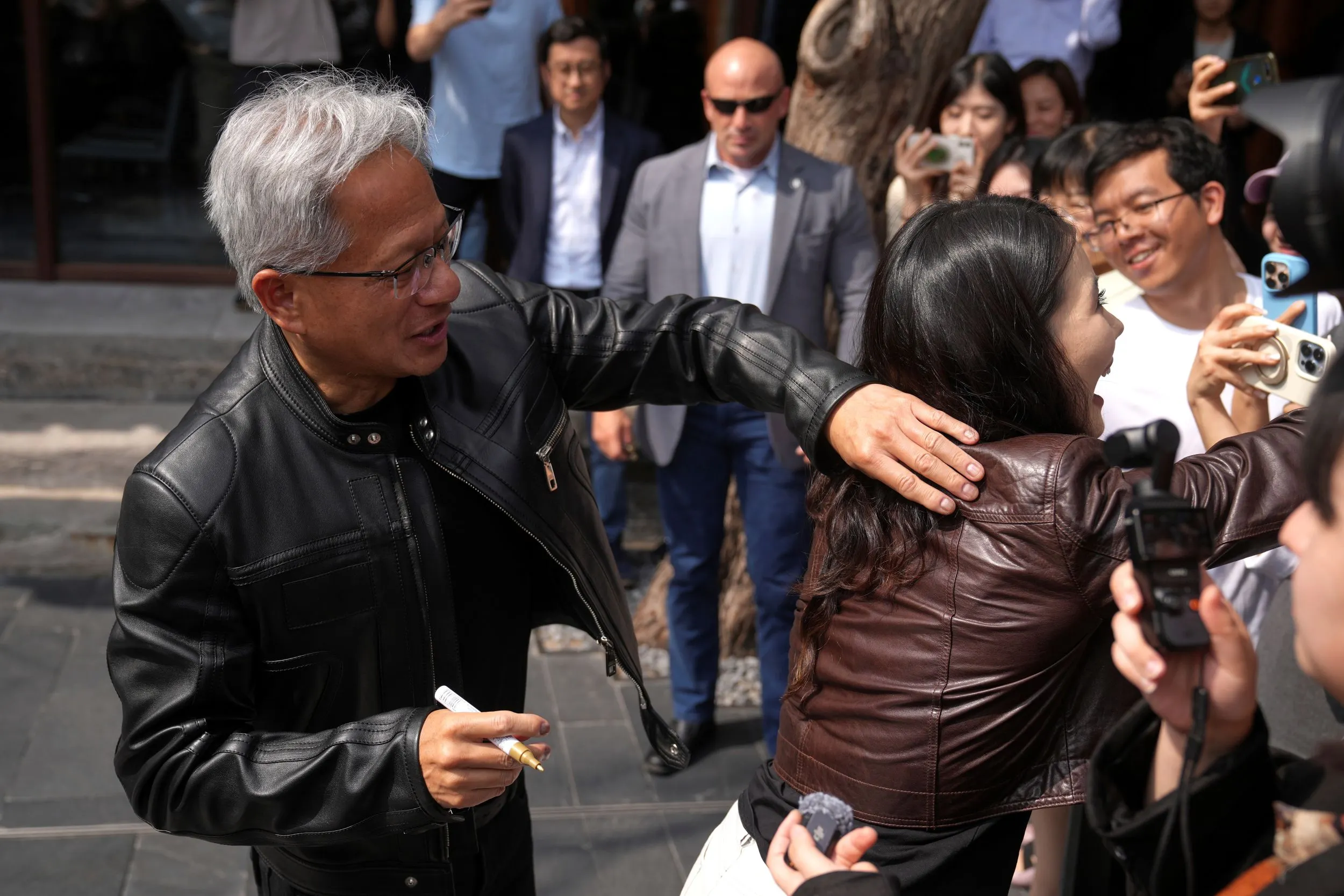 輝達執行長黃仁勳在北京替粉絲簽名。（美聯社）