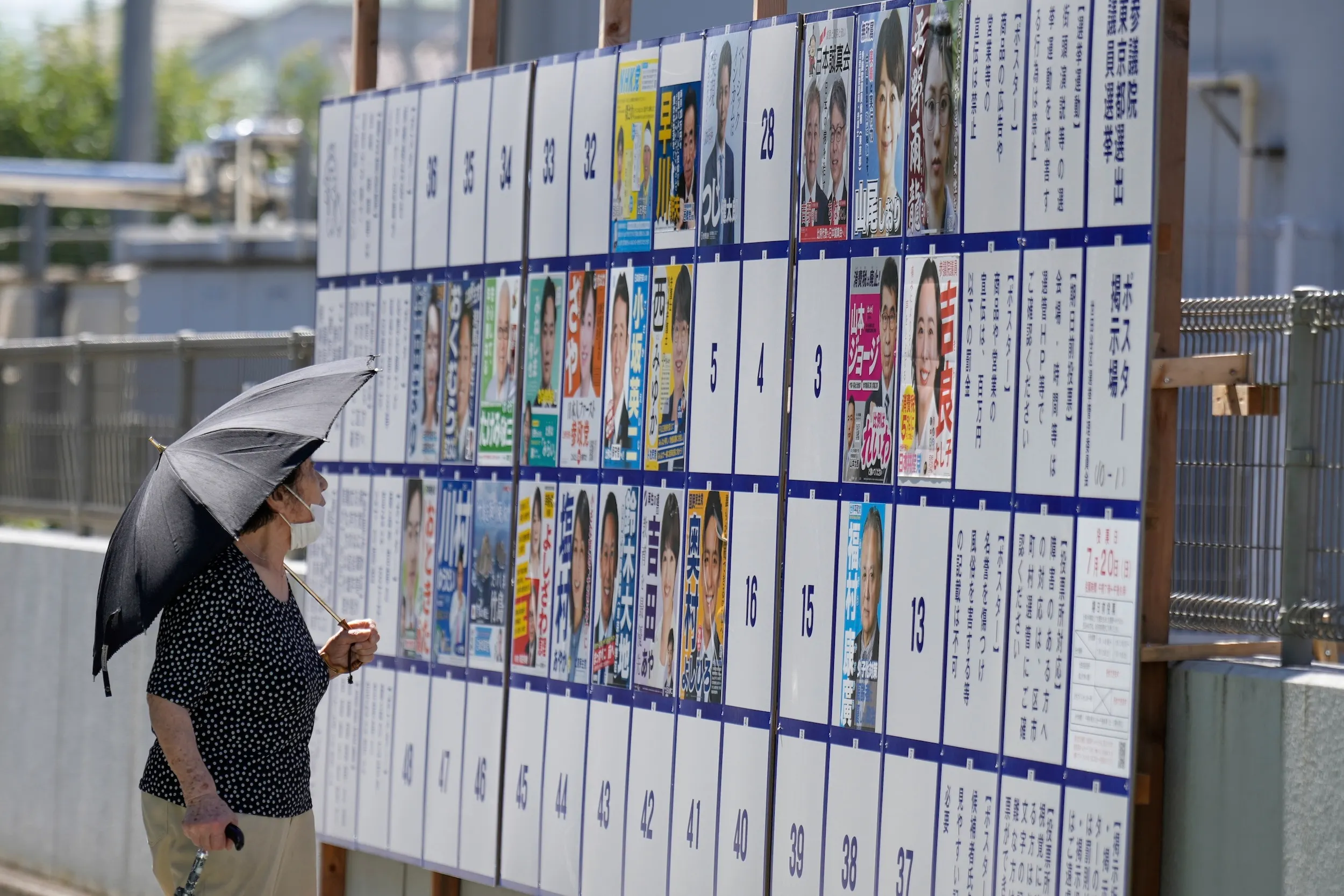2025年7月20日，日本舉行參院大選，一位民眾在東京街頭駐足觀看選舉文宣。（美聯社）