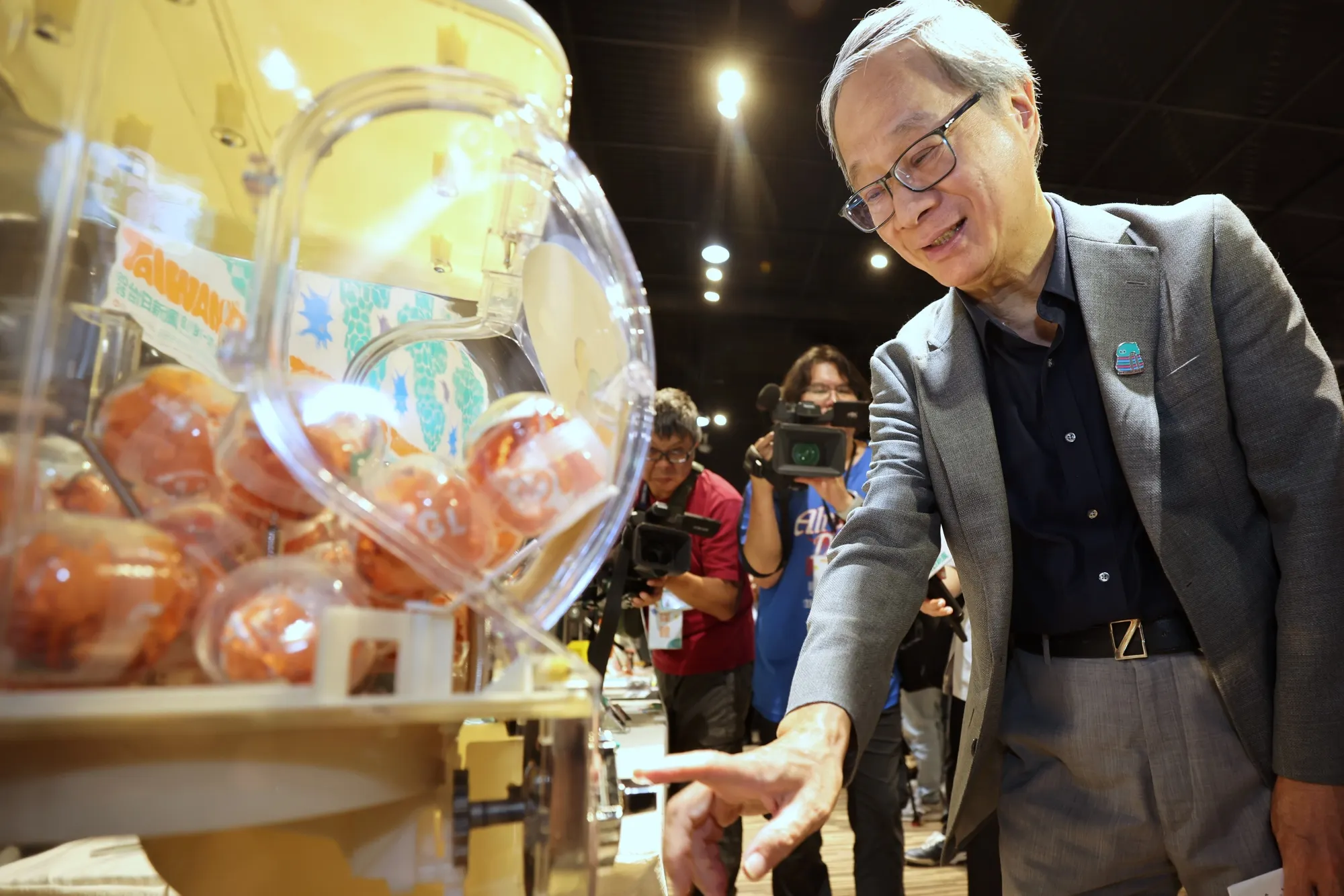 文化部長李遠轉動玻璃紙鎮a-We扭蛋機，彷彿自己已置身於臺灣在大阪文化世博的展演現場。（圖／文化部提供）