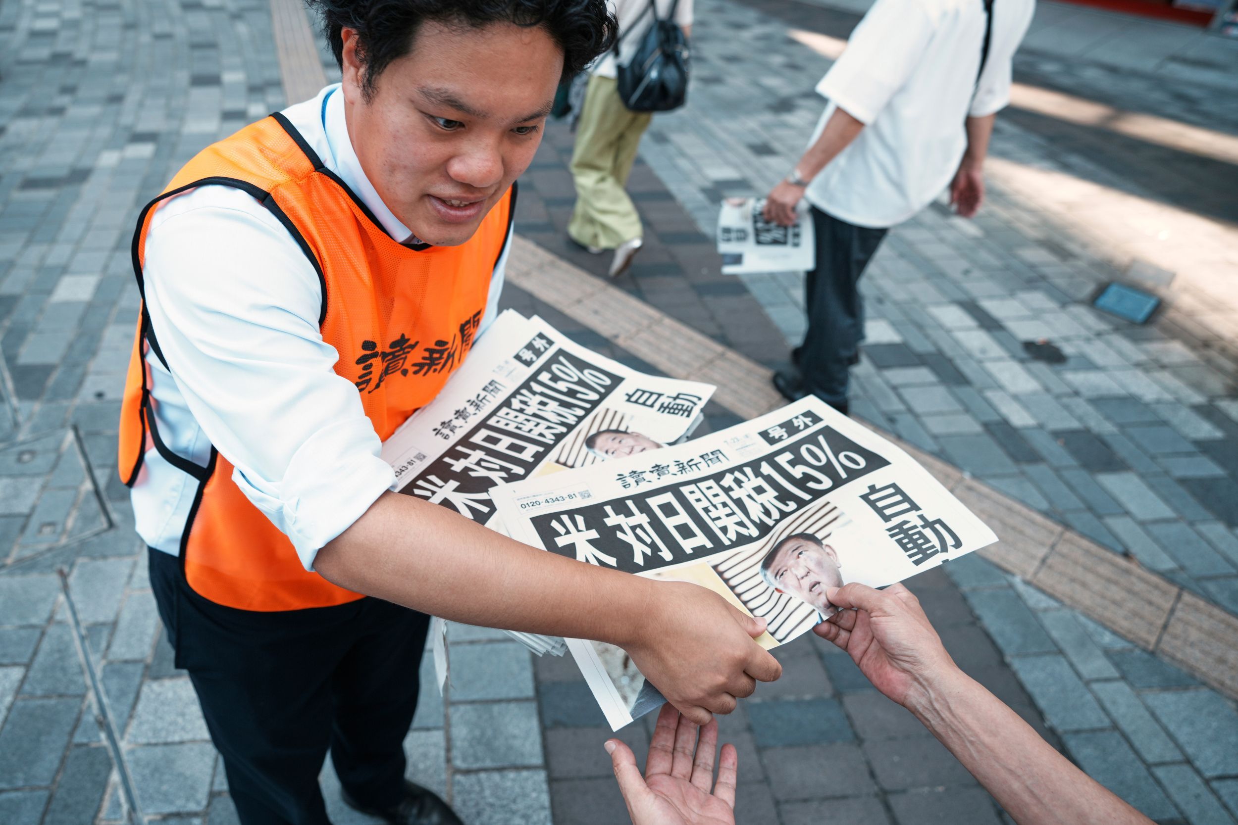 読売新聞が東京の街頭で「日米新関税」の号外を配布。（AP通信）