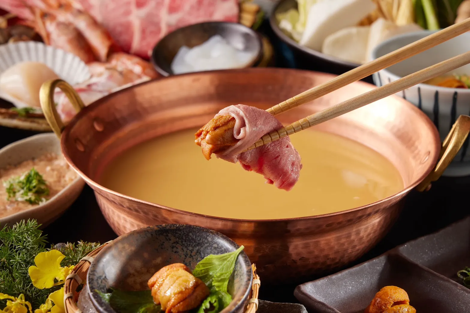 20250724-黑毛屋本家推出夏季限定「黃金海膽涮涮鍋」主打以海膽泥熬製湯底，搭配A5日本和牛、西班牙Bellota伊比利豬與龍膽石斑等海陸高檔食材。（黑毛屋本家提供）