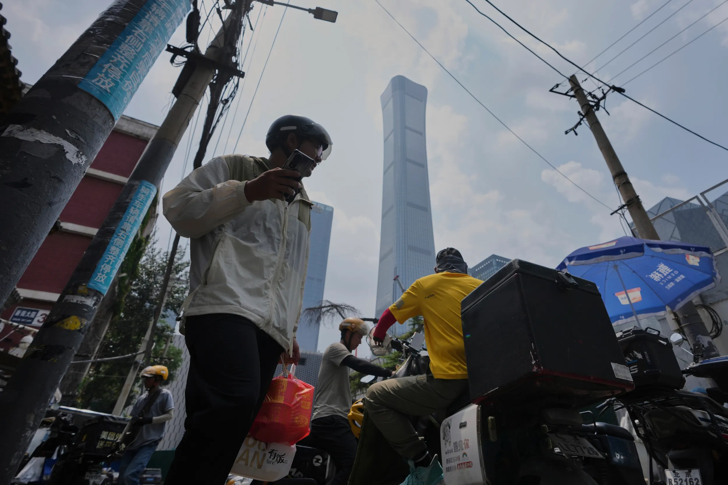 2025年7月23日，外送員在北京中央商業區、首都最高樓「中國尊」大樓附近送餐。（美聯社）