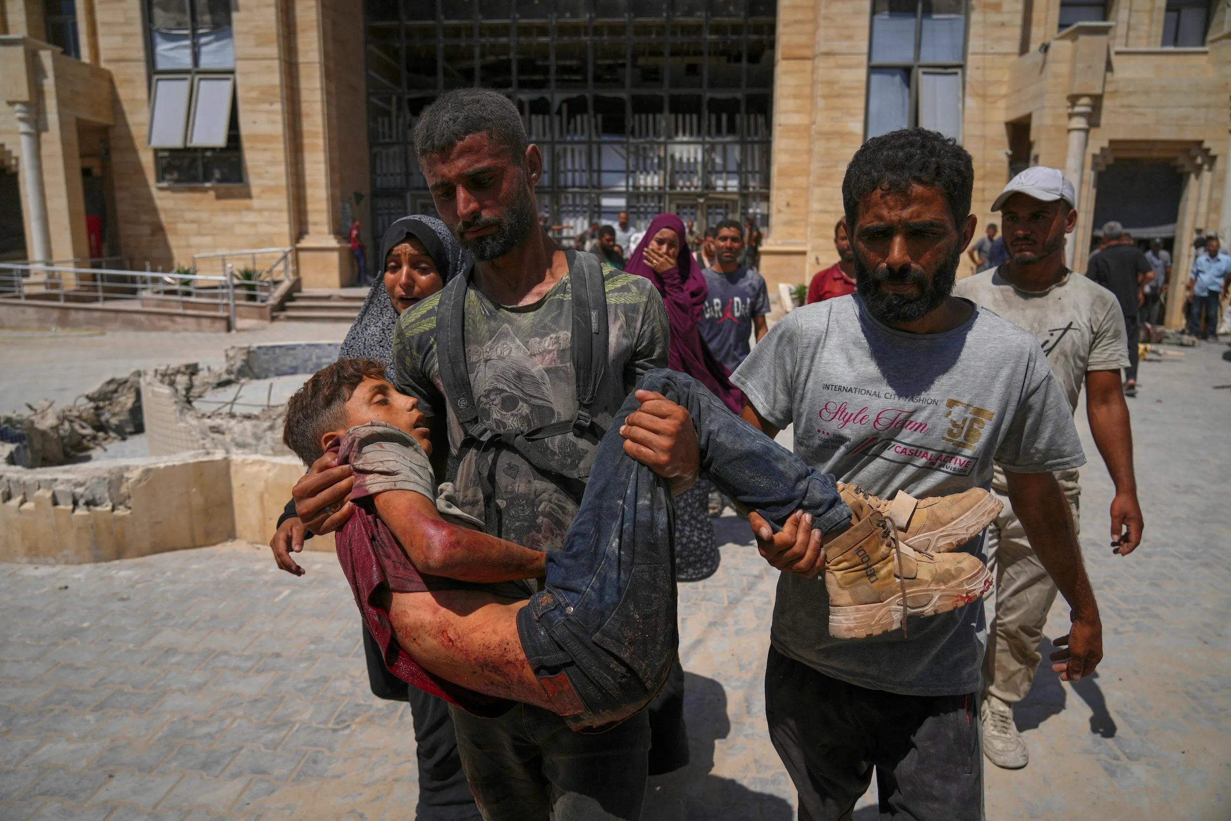 2025年8月1日，在北加薩拜特拉希亞（Beit Lahia），哈瑪德卡達醫院外，一名巴勒斯坦男子抱著喪命的青年遺體。該青年在試圖接近運送人道物資的卡車時遭擊斃。（美聯社）