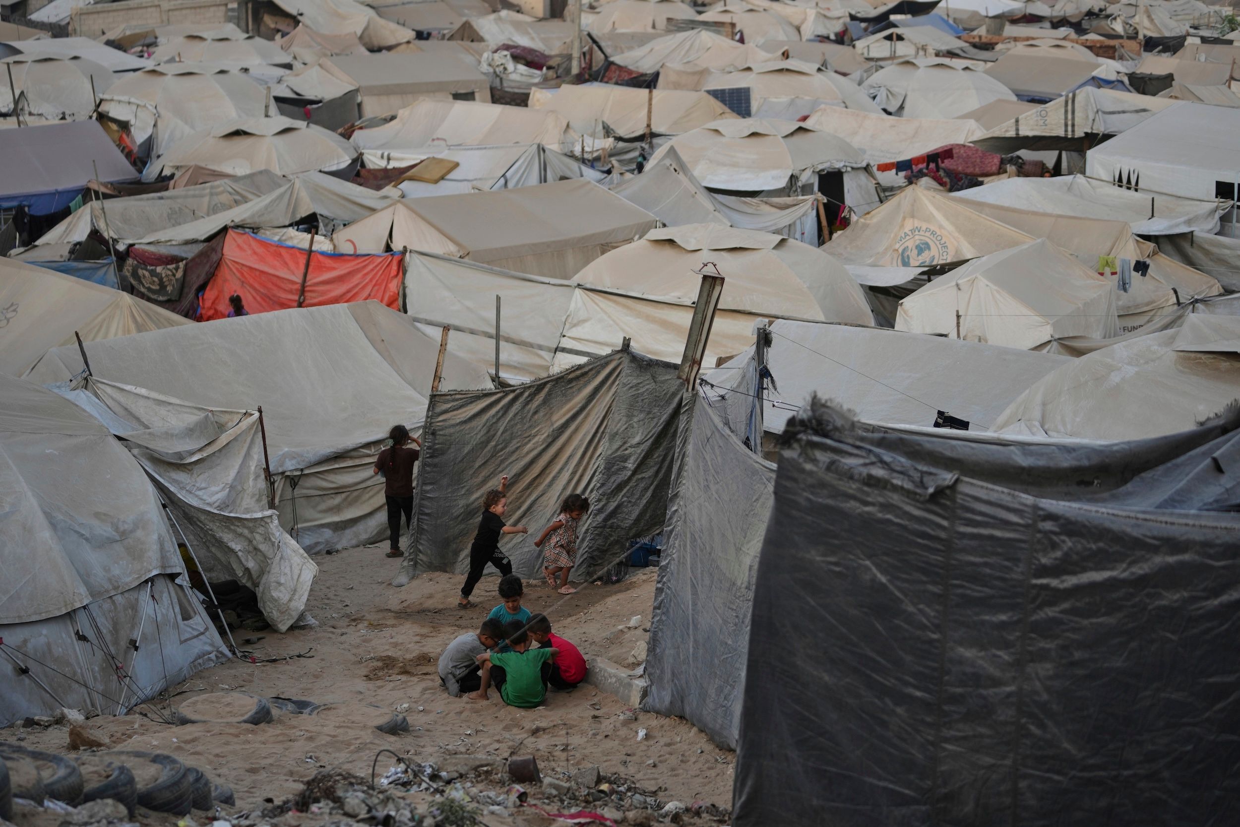 2025年8月3日，加薩市一處流離失所者的帳篷營地，孩童在營區中玩耍，戰火讓無數家庭被迫逃離家園。（美聯社）