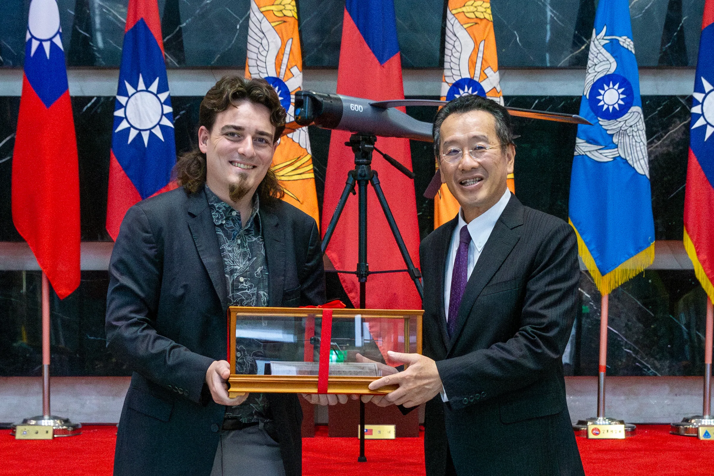 美國Anduril公司創辦人Palmer Luckey（左）致贈國防部長顧立雄（右）無人機模型。（國防部提供）