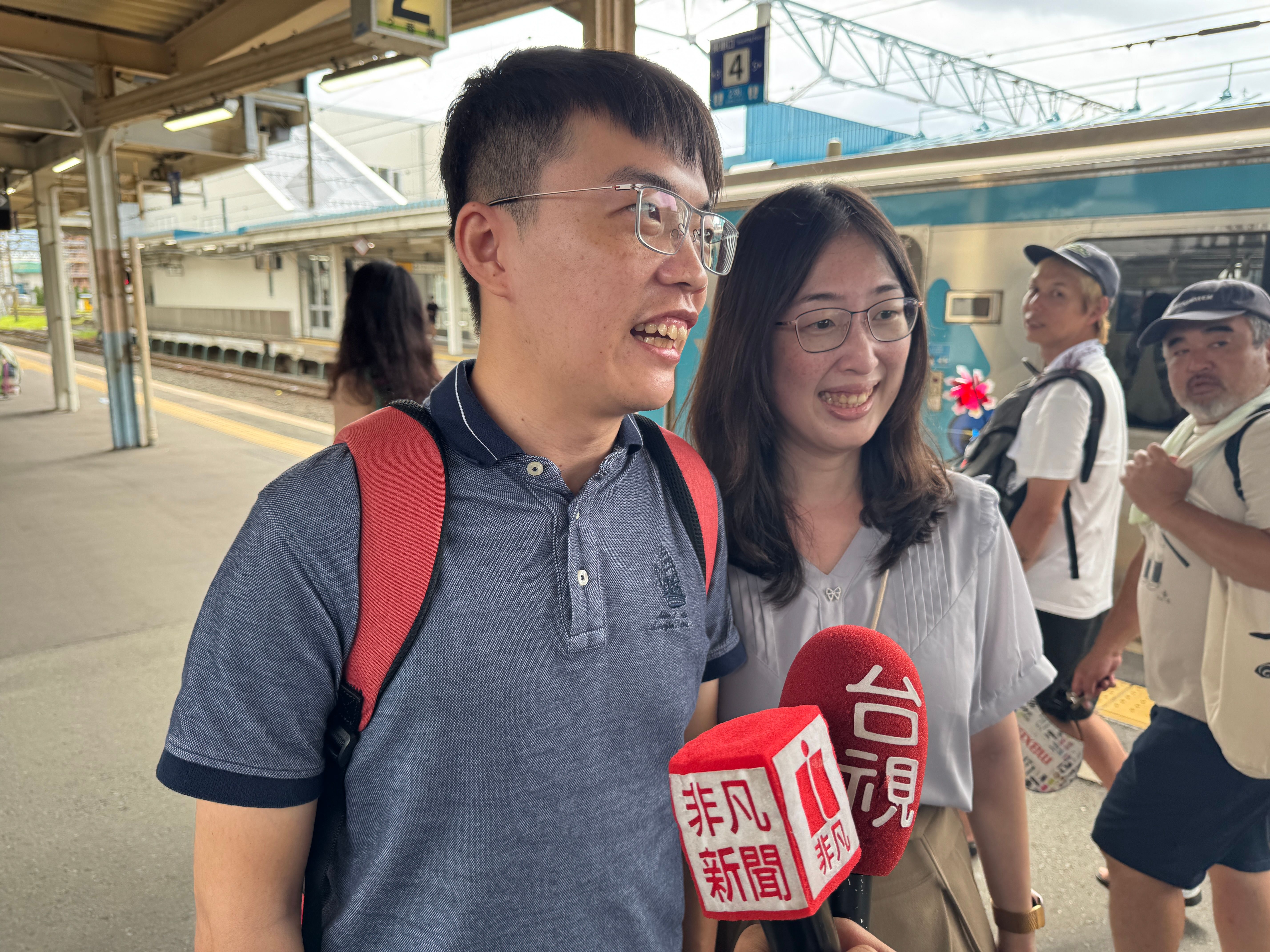 青い森鉄道の台湾ラッピング列車を見つけ、思わず足を止めて記念撮影する台湾からの観光客夫婦。「まさか青森で台湾の列車に出会えるとは！」と笑顔で語った。黃信維