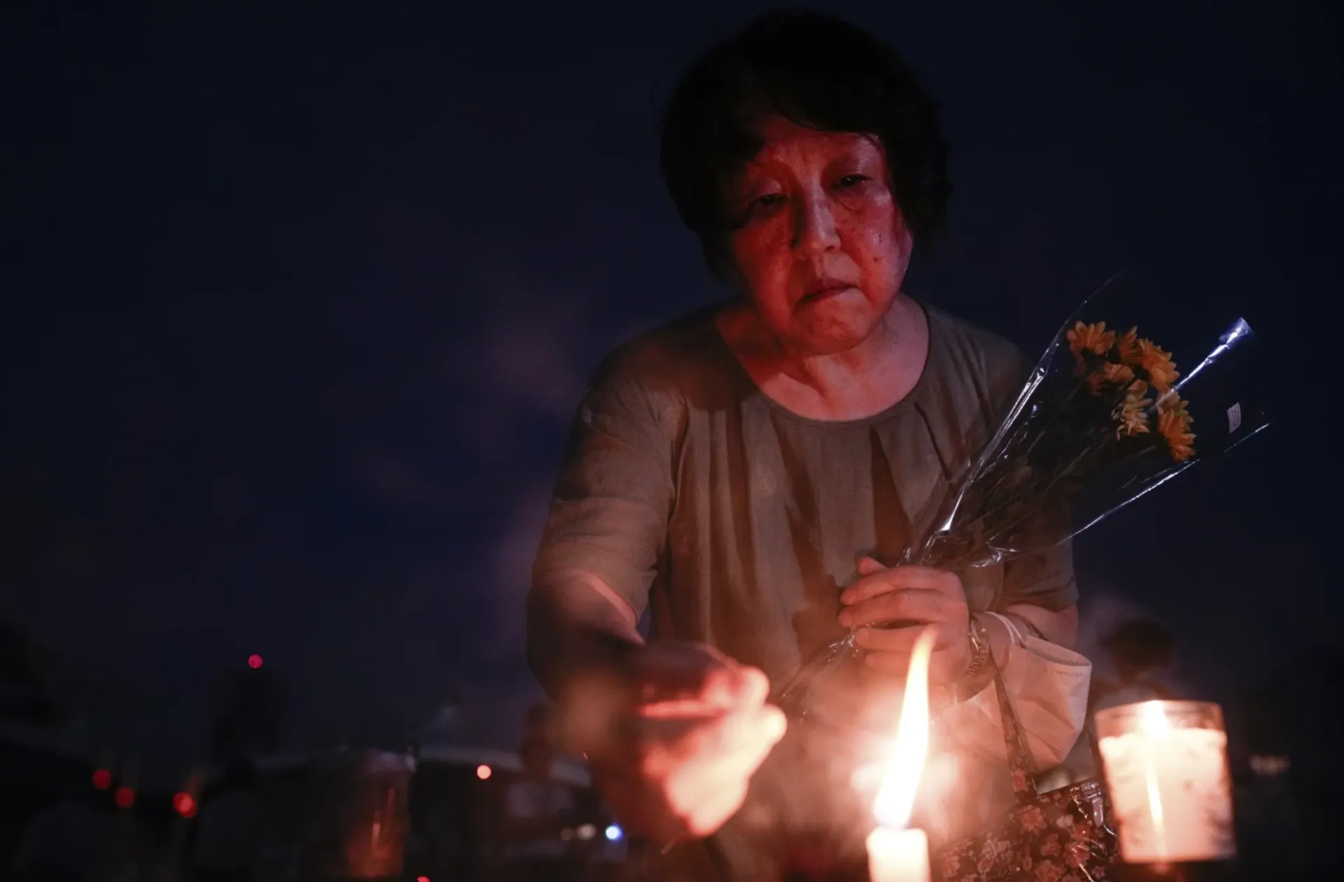 2025年8月6日，一位民眾來到廣島和平紀念公園，為逝者點蠟燭祈禱。（美聯社）