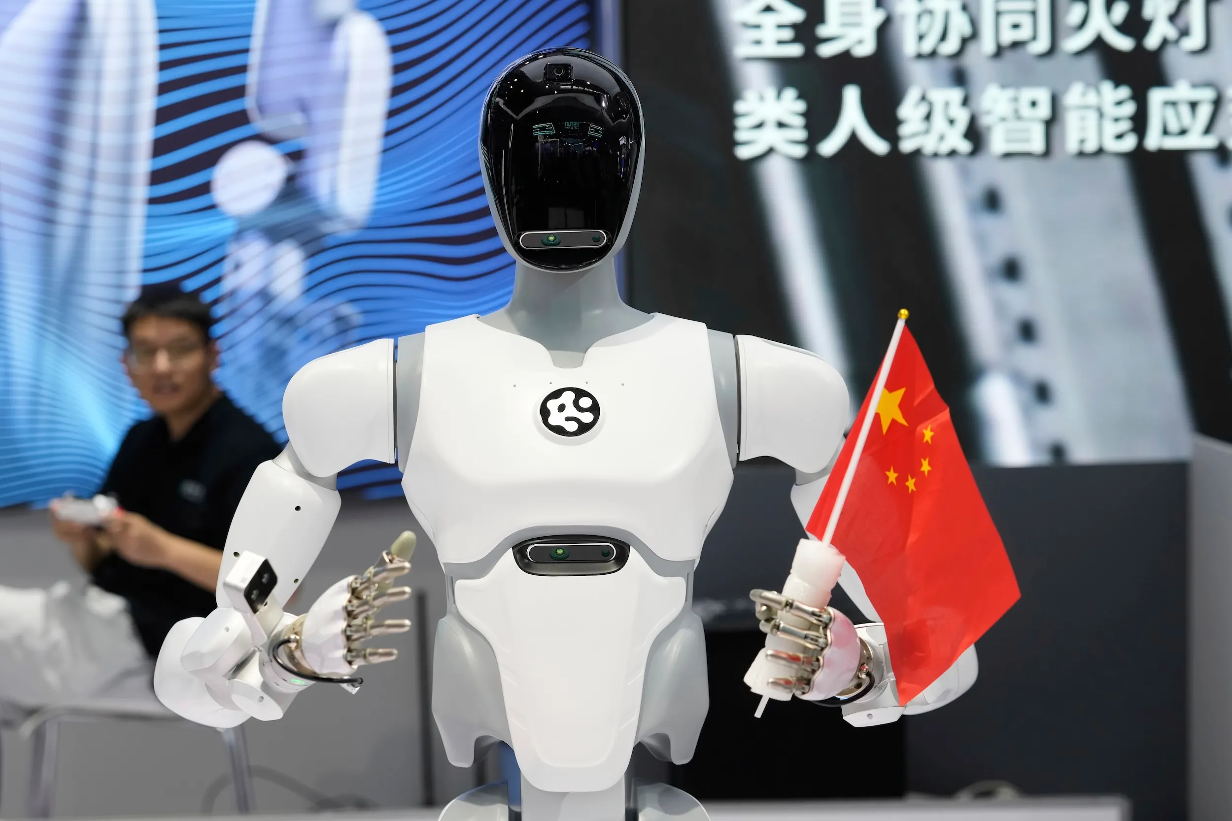 2025年8月8日，中國北京2025世界機器人大會首日，一台人形機器人手持中國國旗。（美聯社）