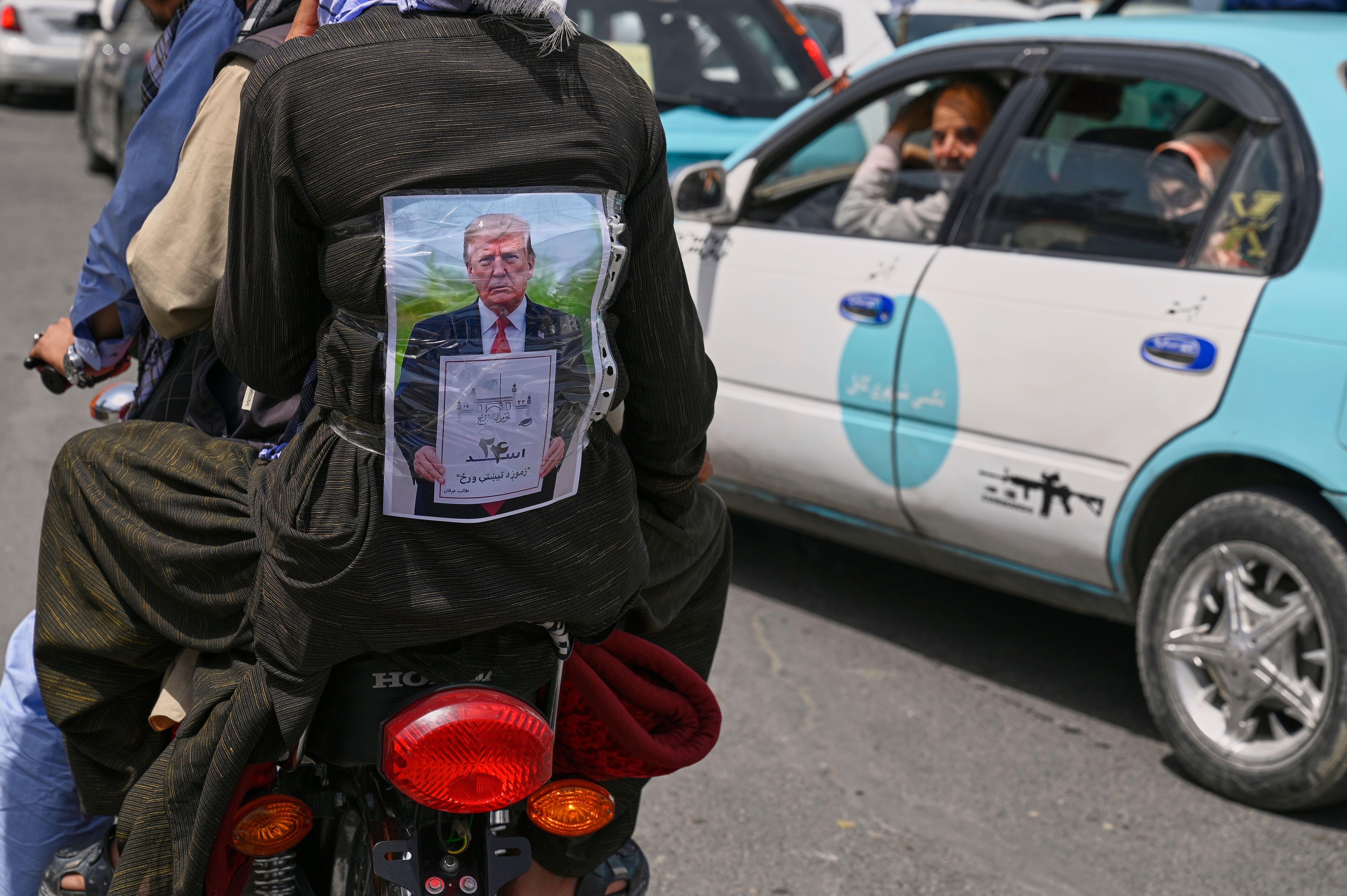 2025年8月，阿富汗民眾在喀布爾街頭慶祝美軍撤離四週年，有人把川普畫像貼在背上。（美聯社）