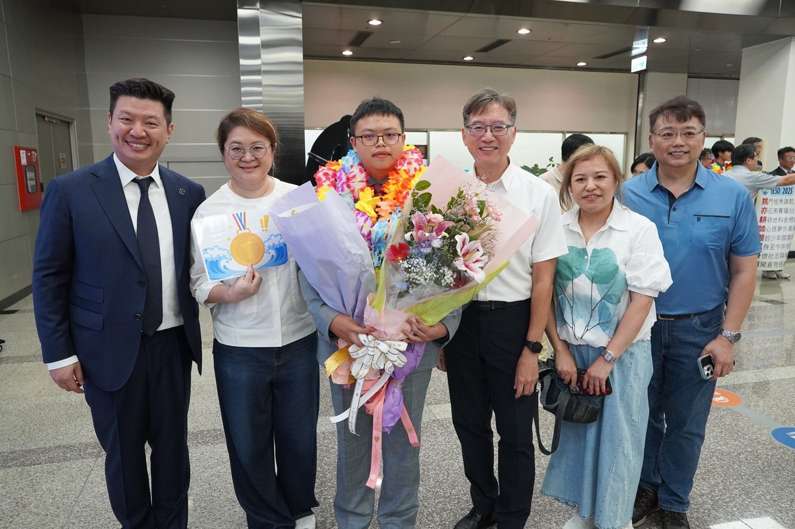 何海銘奪奧林匹亞競賽雙金佳績（中間戴花圈者）、財團法人薇閣公益文教基金會董事長李承宗（左一）、薇閣中學校長孫明峯（右三）、薇閣中學導師陳慧芳（左二）、何海銘父母（右一、二）。（圖／ 薇閣中學提供）